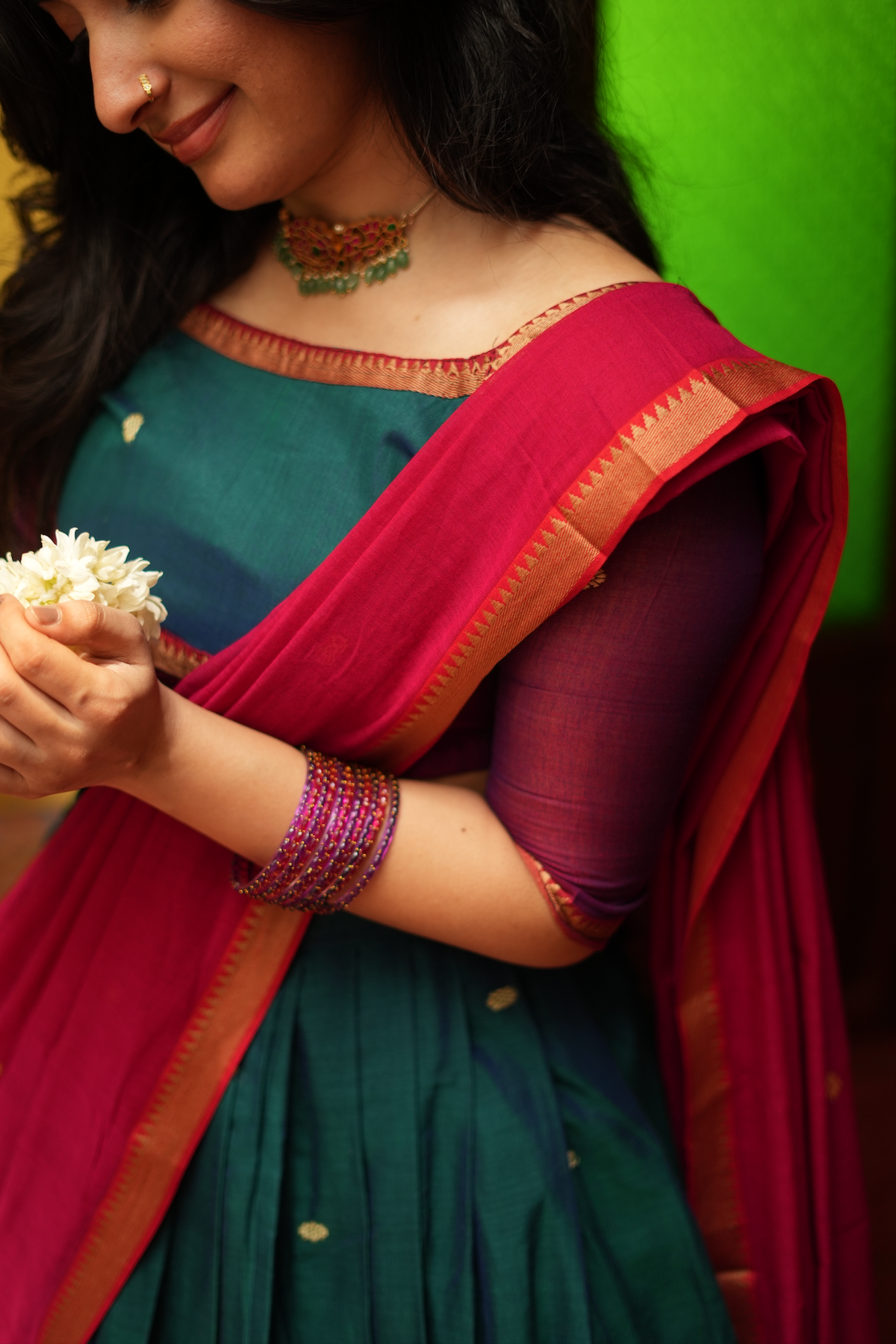Close-up of the green and red handloom half saree showcasing the traditional blouse design, woven borders, and vibrant drape.