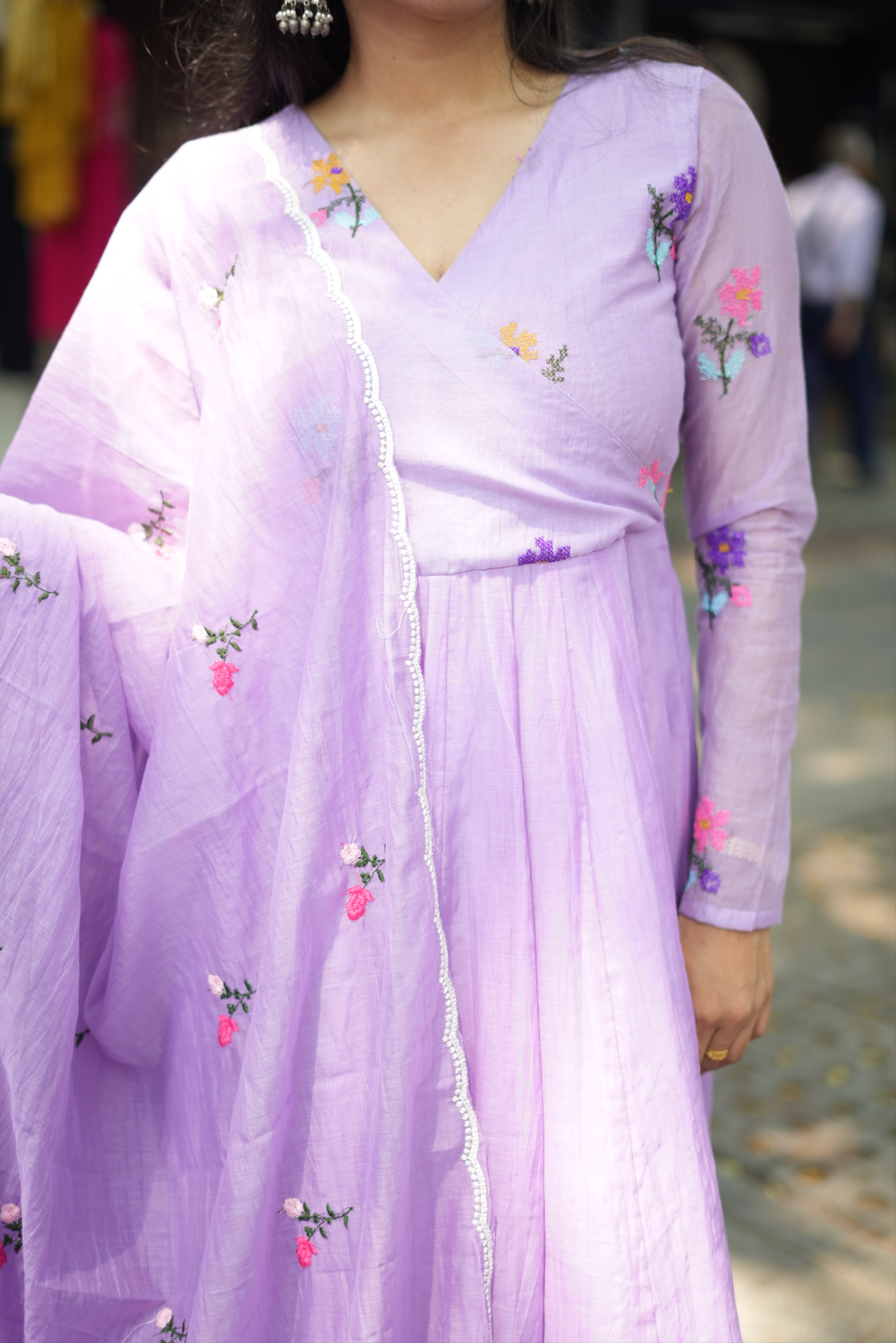 Close-up of floral embroidery on a violet cotton Anarkali dress, highlighting intricate handcrafted motifs and premium fabric.